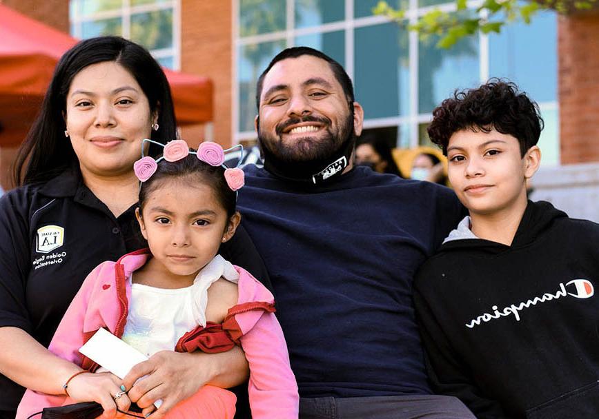 Two parents sitting with their small children, smiling.